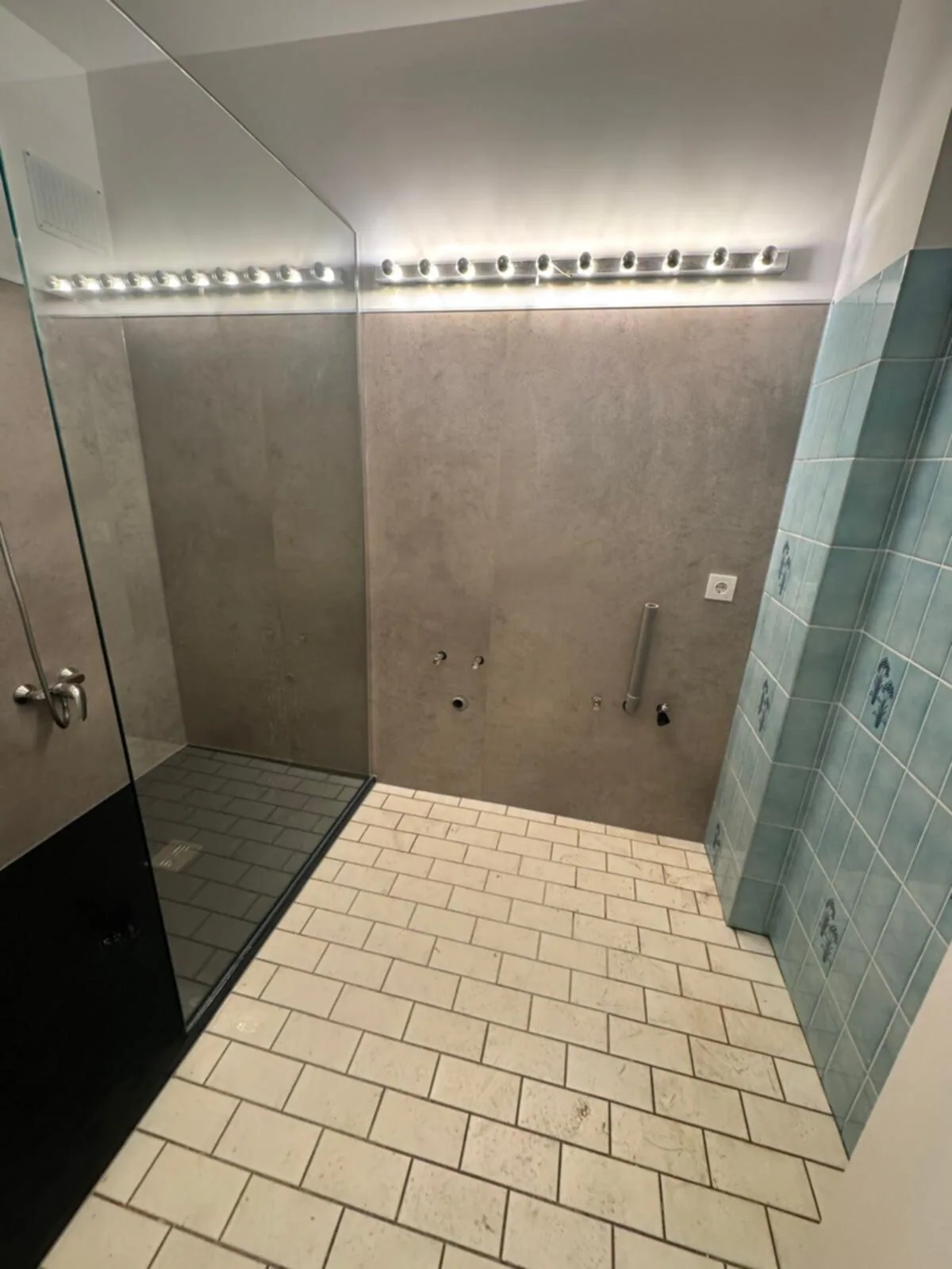 Douche met betonlook wandpanelen en glazen wand, kraan en beugels nog niet gemonteerd