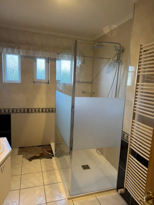Nieuwe inloopdouche met deels matte glazen wand op de plek van het oude bad, onder drie kleine ramen