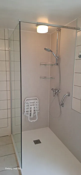 Inloopdouche met lichte wandpanelen, opklapbaar douchezitje, steunbeugel en glazen wand
