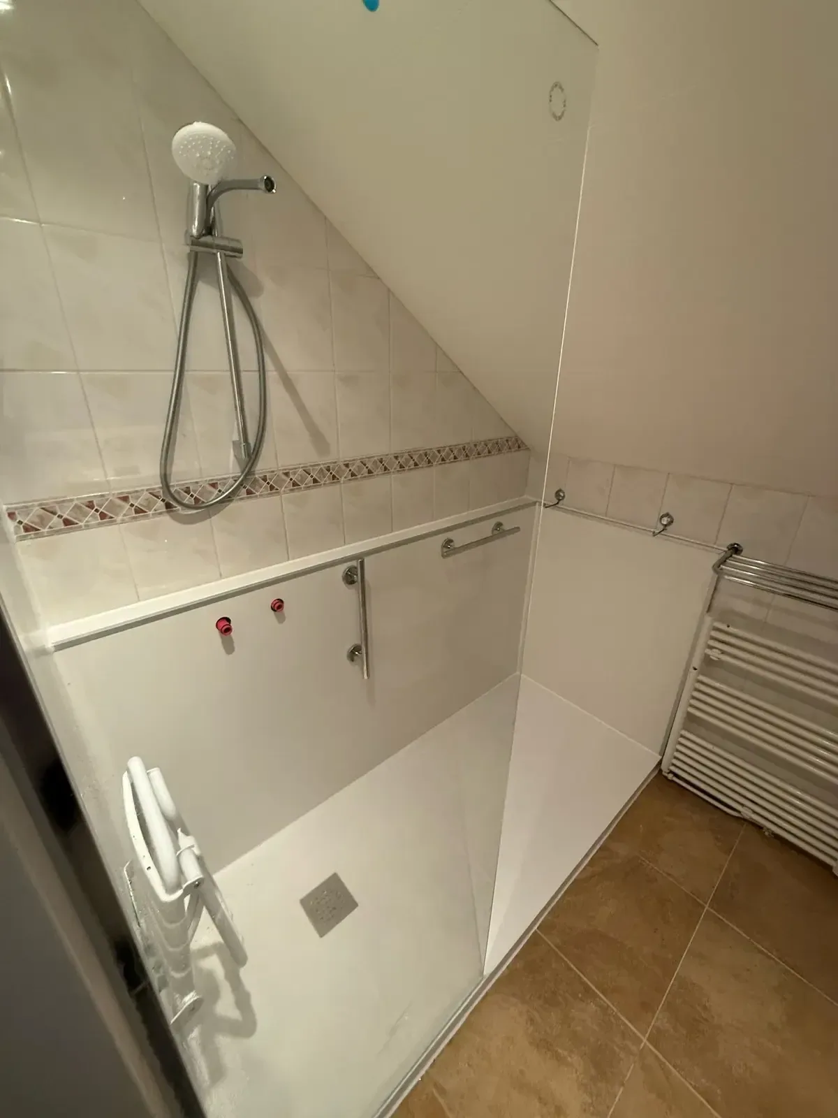 Zolderdouche met witte panelen, opklapbaar zitje, steunbeugels en handdoekradiator